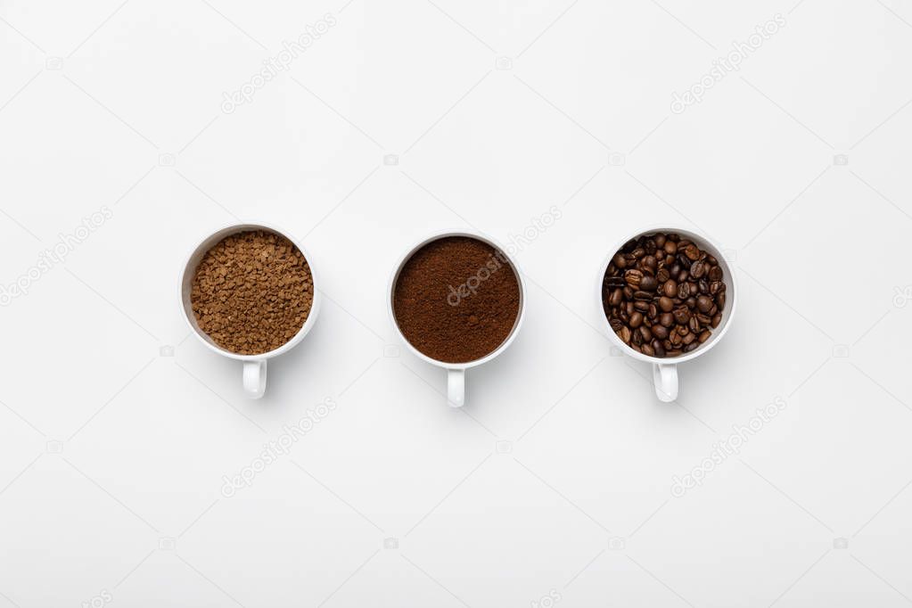 flat lay with three types of coffee grinding in cups on white background with copy space