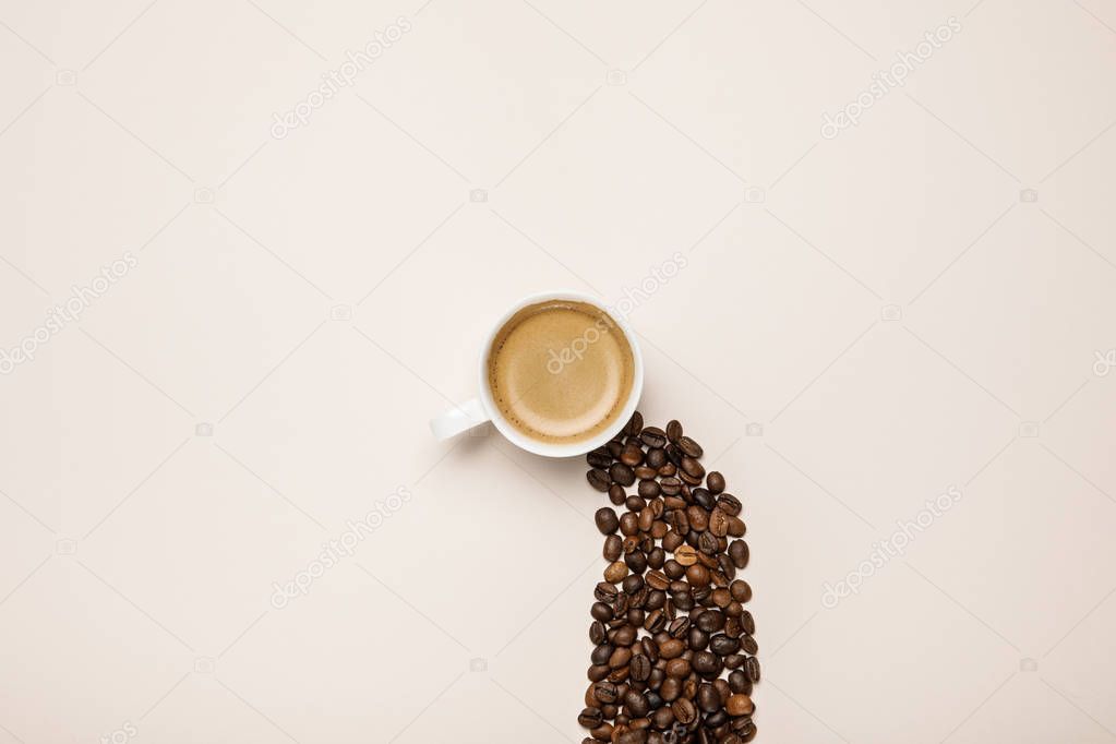 top view of cup with fresh coffee near coffee grains on beige background