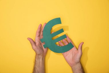 Adam sarı üzerinde Euro para birimi işareti tutan kırpılmış görünümü