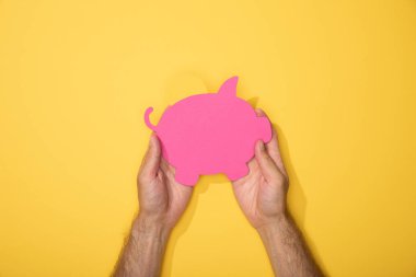 sarı üzerinde pembe kağıt kumbara tutan adam kırpılmış görünümü
