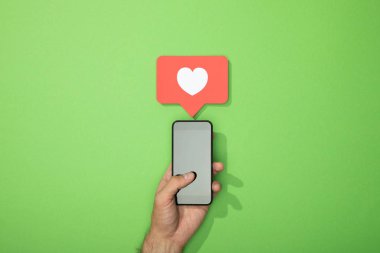 yeşil üzerinde Gadget yukarıdaki simgeye beyaz kalp ile adam tutan Smartphone kırpılmış görünümü