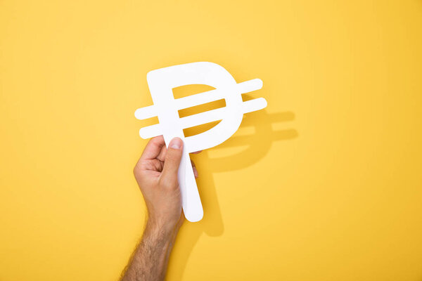 cropped view of man holding paper peso currency signs on yellow