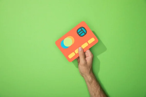 裁剪视图的人拿着红色纸图标的信用卡在绿色 — 图库照片