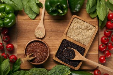 doğrama tahtası üzerinde olgun sebze ve kaşık yakın kaselerde beyaz, kırmızı ve siyah Quinoa üst görünümü