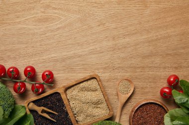 domates, ıspanak yaprakları ve brokoli yakınındaki ahşap kaselerde beyaz, siyah ve kırmızı Quinoa üst görünümü