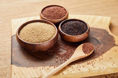 kaşık yakınındaki tahta kaselerde beyaz, siyah ve kırmızı Quinoa