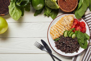 çatal ve fotokopi alanı ile beyaz ahşap masa üzerinde ızgara tavuk göğsü ve sebze ile lezzetli pişmiş Quinoa üst görünümü