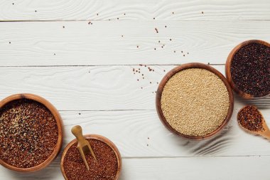 beyaz dokulu masa üzerinde ahşap kaselerde beyaz, siyah ve kırmızı Quinoa tohumları üst görünümü