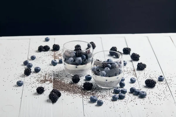 美味的酸奶与嘉种子 黑莓接近分散的种子和浆果上的白色木材隔离在黑色 — 图库照片