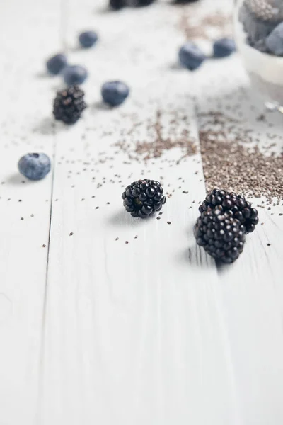 在白色木桌上选择分散的黑莓 蓝莓和奇亚种子 — 图库照片