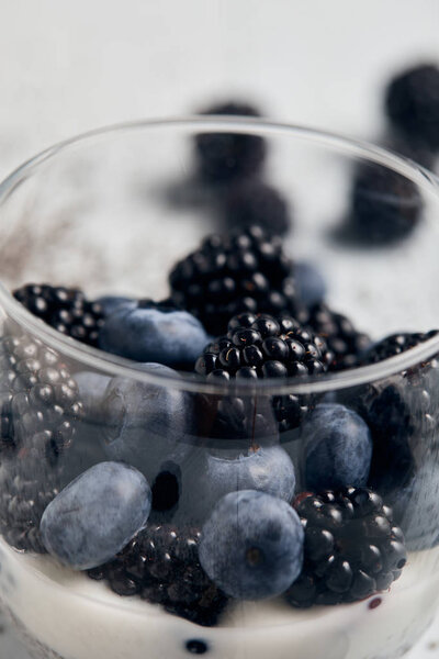 close up view of blackberries, blueberries and yogurt in glass