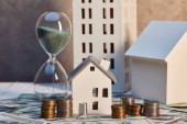 houses models and hourglass on cash and coins, real estate concept