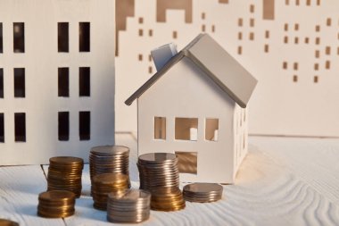 houses models on white wooden table with coins, real estate concept clipart