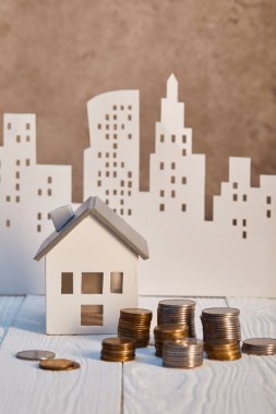 houses models on white wooden table with coins, real estate concept clipart