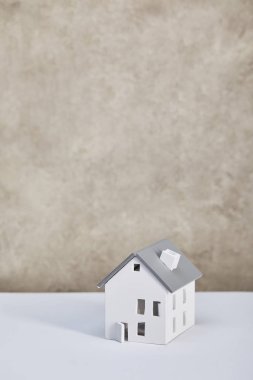 house model on white table near grey textured wall, real estate concept clipart