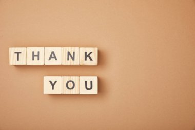 top view of wooden cubes with thank you lettering on beige background with copy space
