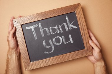 partial view of man holding chalkboard with thank you lettering clipart