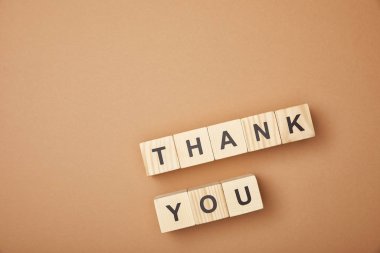 top view of wooden cubes with thank you words on beige background clipart
