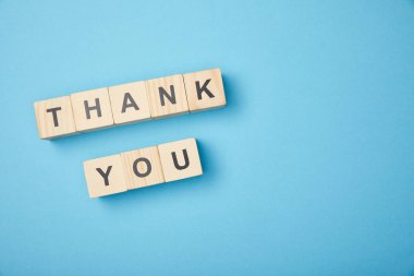 top view of wooden cubes with thank you words on blue background clipart