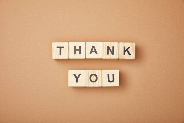 Top view of wooden cubes with thank you lettering on beige background