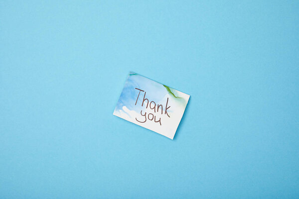 greeting card with thank you lettering on blue background with copy space