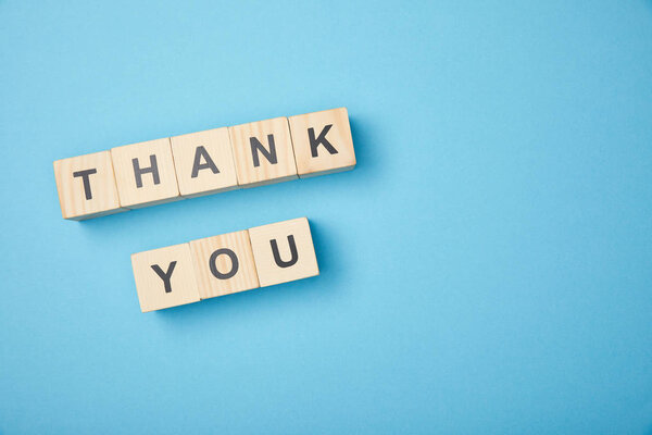 top view of wooden cubes with thank you words on blue background
