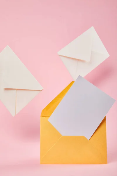 ピンクの背景に文字の近くに空白の白いカードを持つ黄色の封筒 — ストック写真