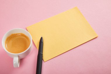 pembe arka planda kalem ve kahve bardağı ile sarı zarf