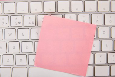 Dizüstü klavyede boş pembe yapışkan not üst görünümü 