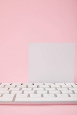pembe arka planda bilgisayar klavyesi yakınında boş beyaz kart görünümü yakın