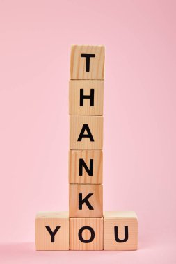 wooden cubes with thank you lettering on pink background clipart