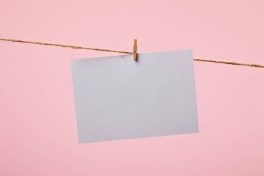 white empty card hanging on rope isolated on pink clipart