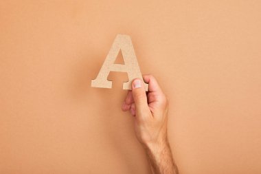 adam tutan kağıt kırpılmış görünümü, bej arka planda A mektubu kesti