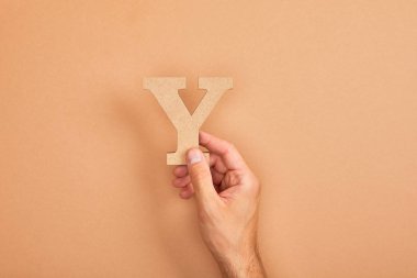 adam tutan kağıt kırpılmış görünümü, bej arka planda Y kesim harfi