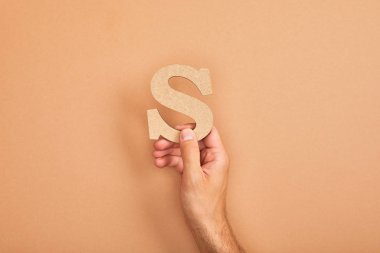 cropped view of man holding paper cut letter S on beige background clipart