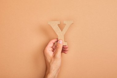 adam tutan kağıt kesme harfi kısmi görünümü bej arka planda Y