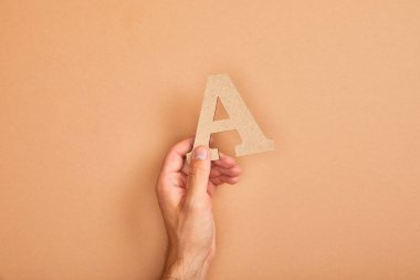 adam tutan kağıt kesilmiş harf kısmi görünümü bej arka planda A