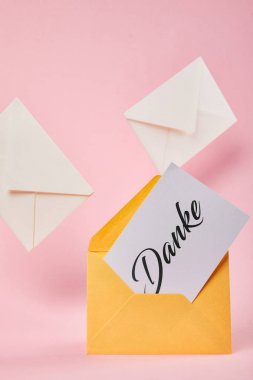 yellow envelope with danke word on white card near letters on pink background clipart