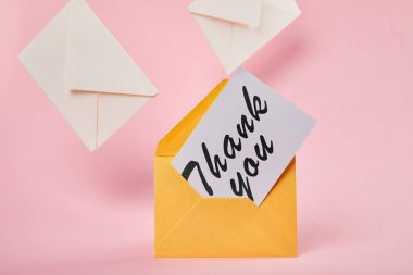 yellow envelope with thank you lettering on white card near letters on pink background clipart