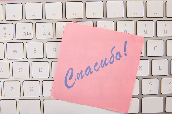 top view of pink sticky note with thankful lettering in russian on laptop keyboard