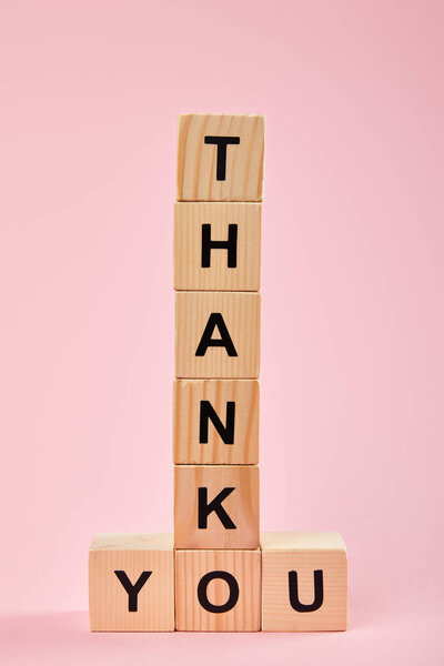 wooden cubes with thank you lettering on pink background