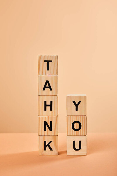 wooden blocks with thank you lettering on table isolated on beige