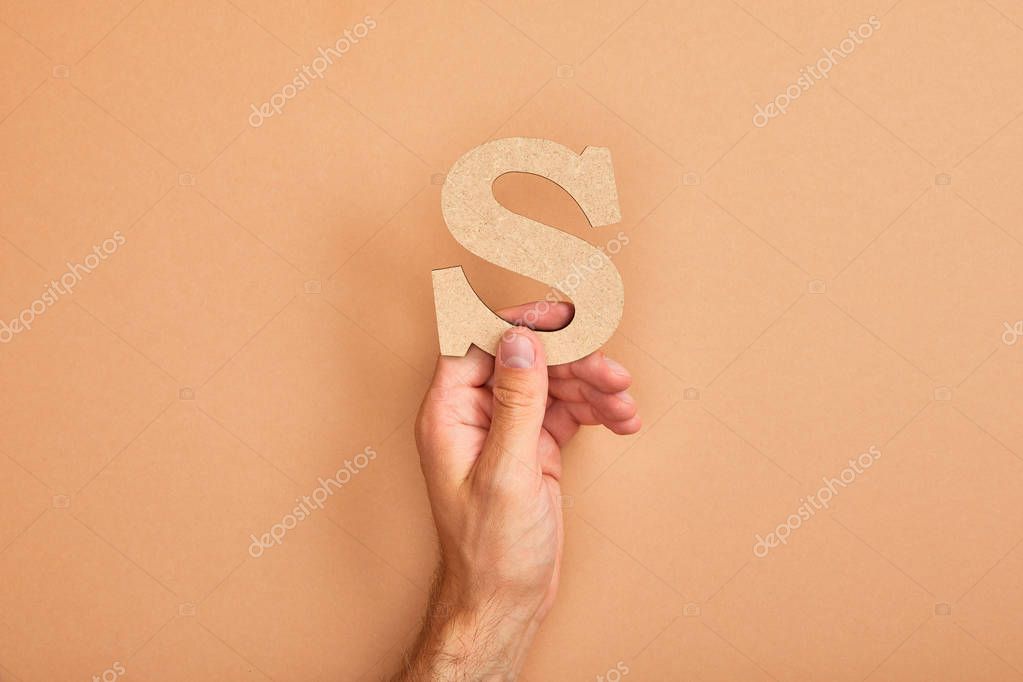 Partial view of man holding paper cut letter S on beige background