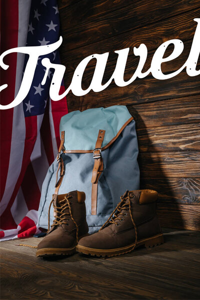 trekking boots, backpack and american flag on wooden surface with travel illustration