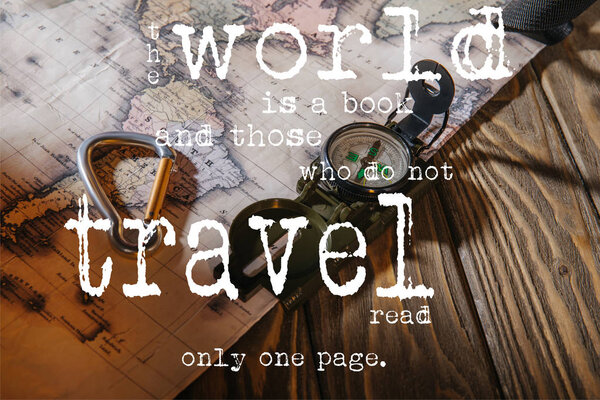 compass, safety hook and map on wooden table with the world is a book and those who do not travel read only one page lettering