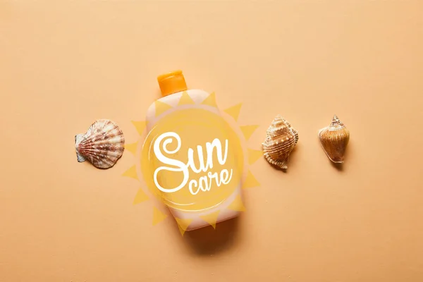 top view of seashells and bottle with suntan lotion on beige background with sun care lettering