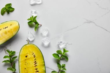 Nane ve buz ile mermer yüzeyinde tohumlar ile kesilmiş lezzetli egzotik sarı karpuz üst görünümü