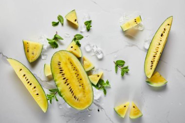 mermer yüzeyinde buz ve nane ile kesilmiş lezzetli egzotik sarı karpuz üst görünümü