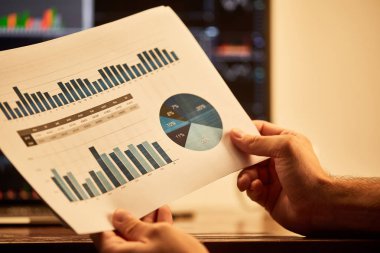 cropped view of adult man holding paper with charts and graphs  clipart