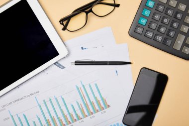 kağıtlar, kalem, hesap makinesi, akıllı telefon, dijital tablet ve gözlük masaüzerinde üst görünümü 